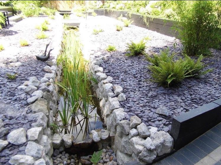 Rock-lined rill water feature with reeds and slate mulch