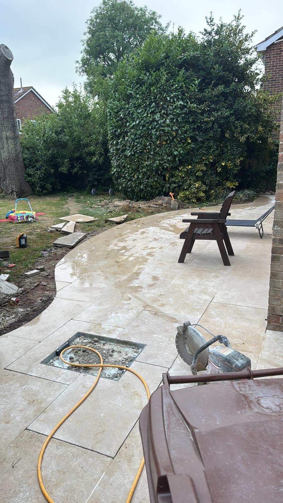 Curved stone patio area with chairs and tools during installation
