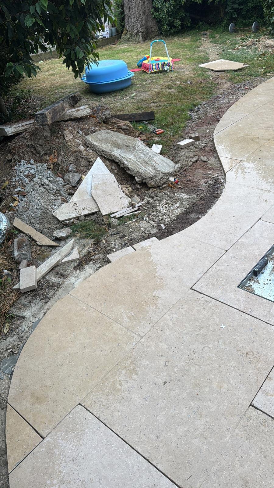 Curved patio edge with excavated soil and broken slabs