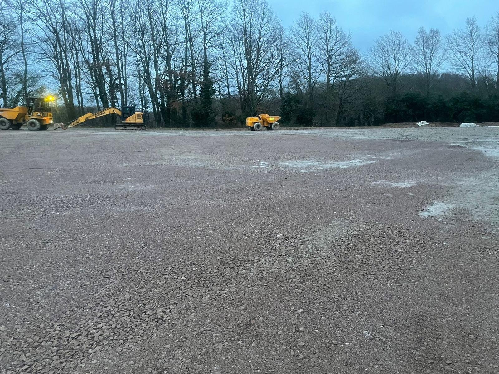 Large gravel surface with construction machinery in the distance